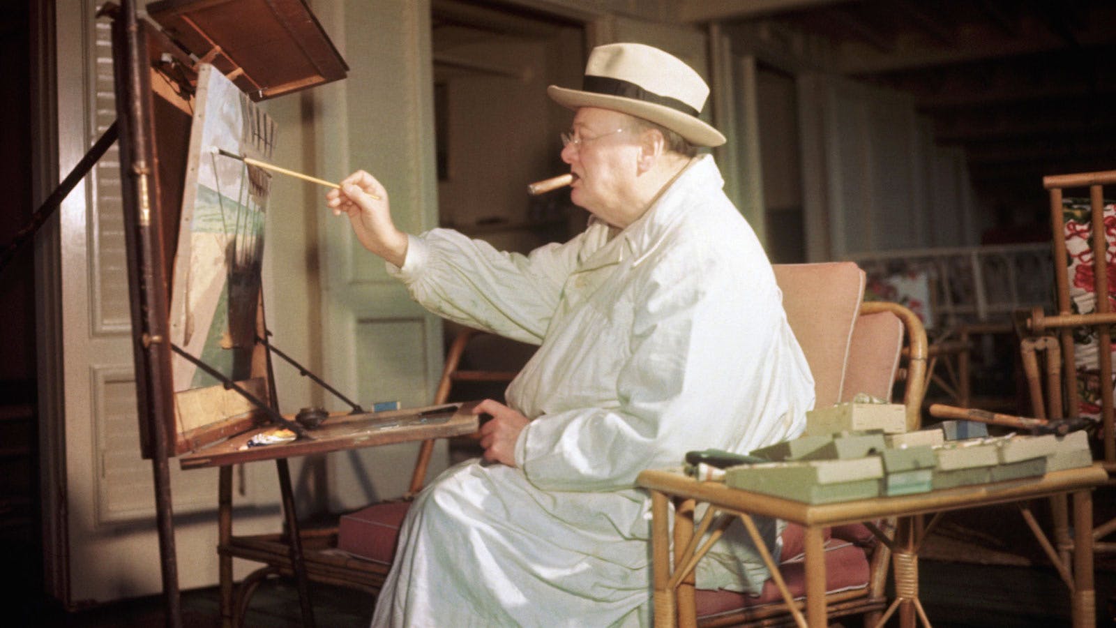 Sir Winston Churchill relaxes while smoking and painting in his art studio.