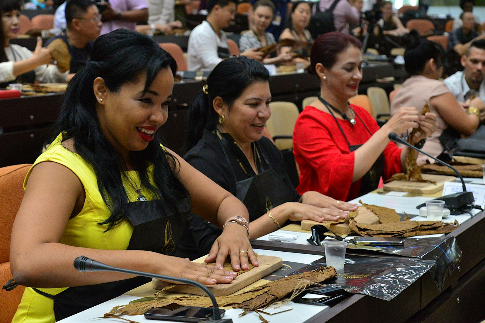 A number of attendees learn how to roll a cigar during an instructional seminar.