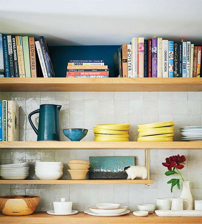 Exposed wood shelving stores a cookbook collection and dishware. Photo by Ty Cole