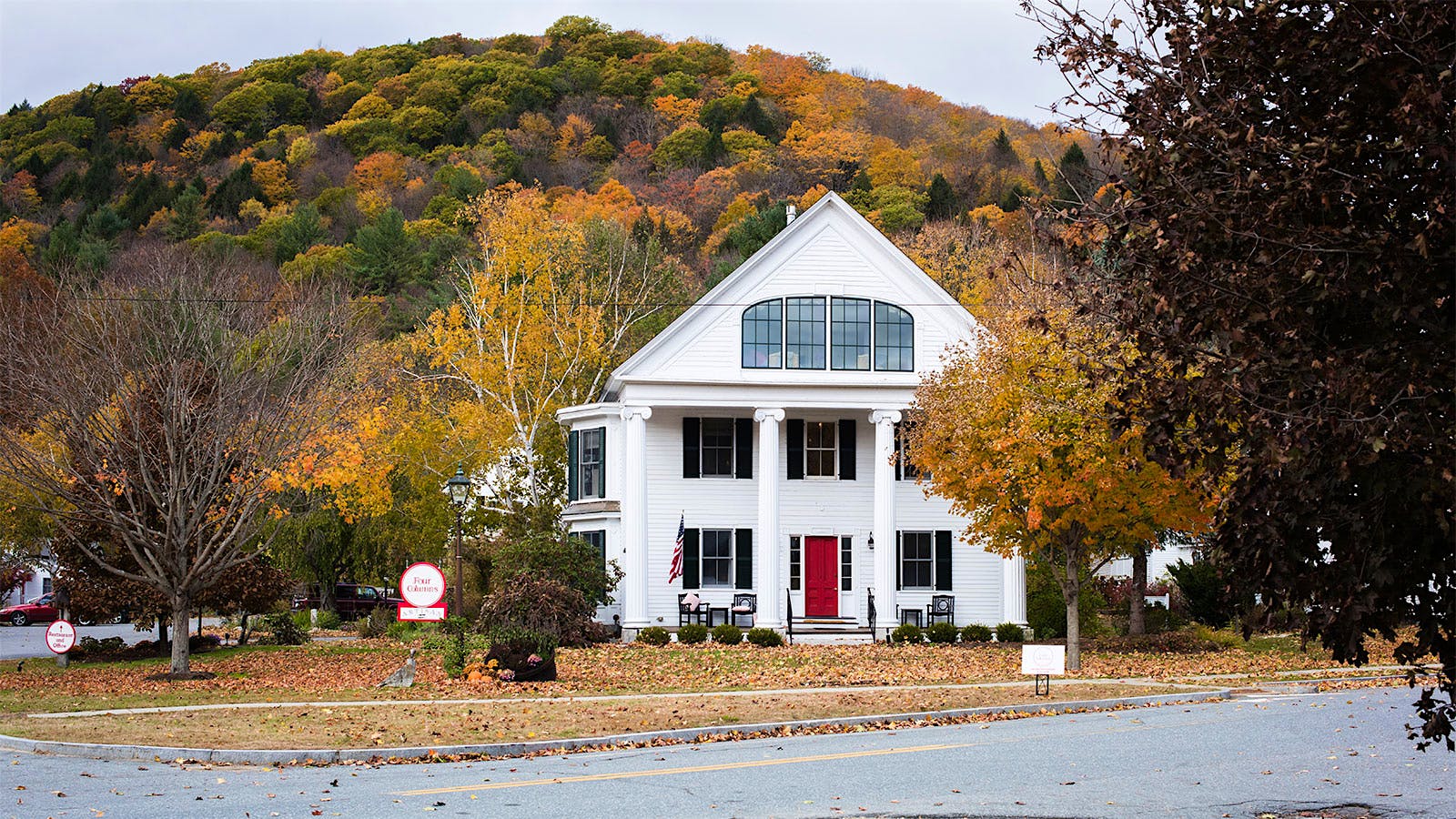 The exterior of Four Columns Inn, with fall-colored foliage in the background