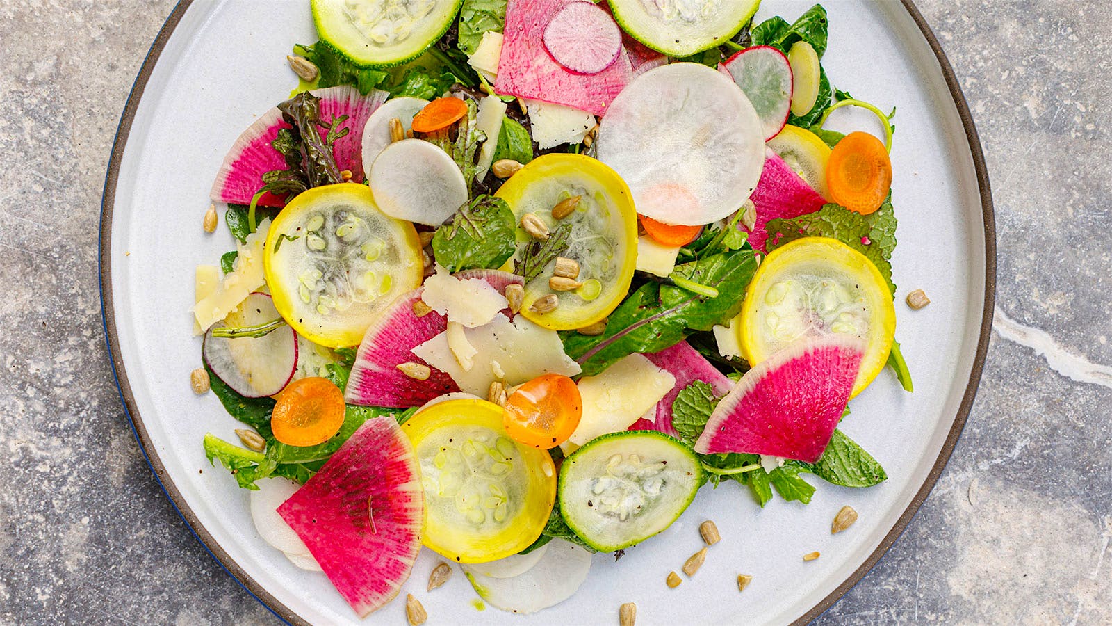 A colorful salad with green and yellow zucchini, radishes, carrots and sunflower seeds