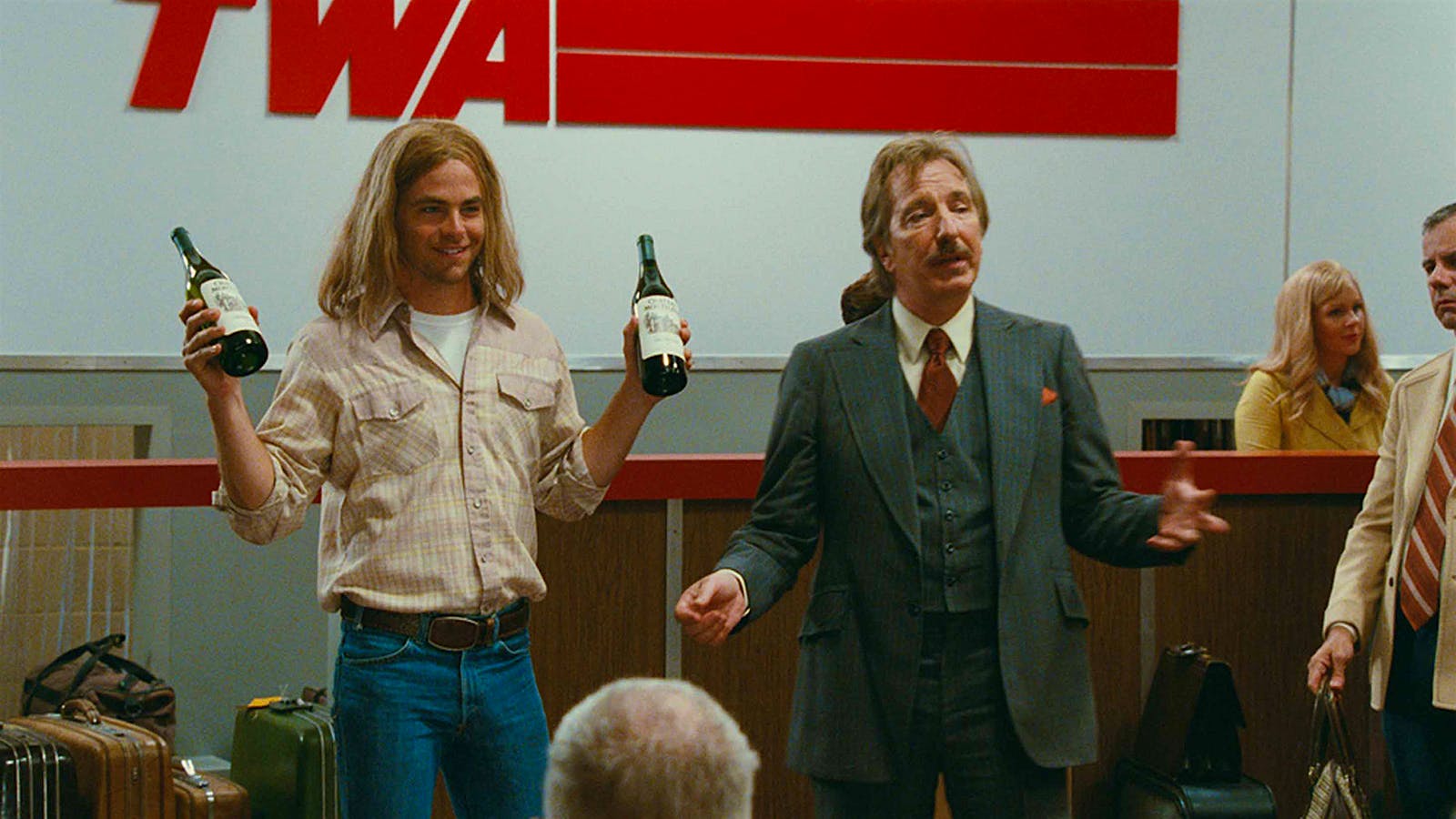 Bo Barrett (Chris Pine), holding up wine bottles, and Stephen Spurrier (Alan Rickman) at the TWA checkin counter