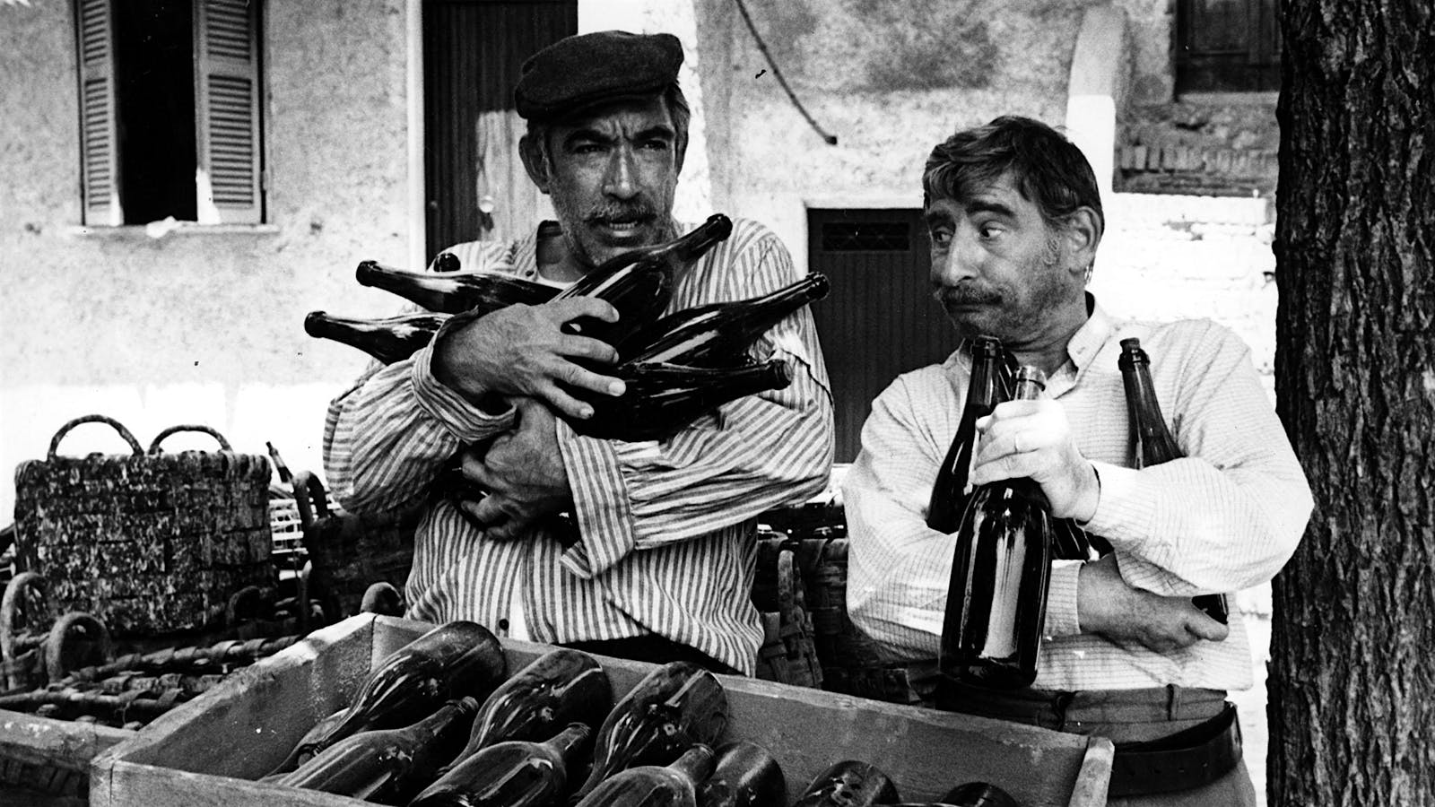 The Secret of Santa Vittoria movie still: Two Italian village men with their arms full of label-less wine bottles.