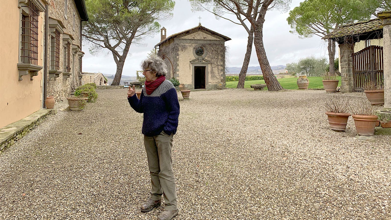 Maurizia di Napoli dressed in casual work clothes stands outside an old stone farmhouse.