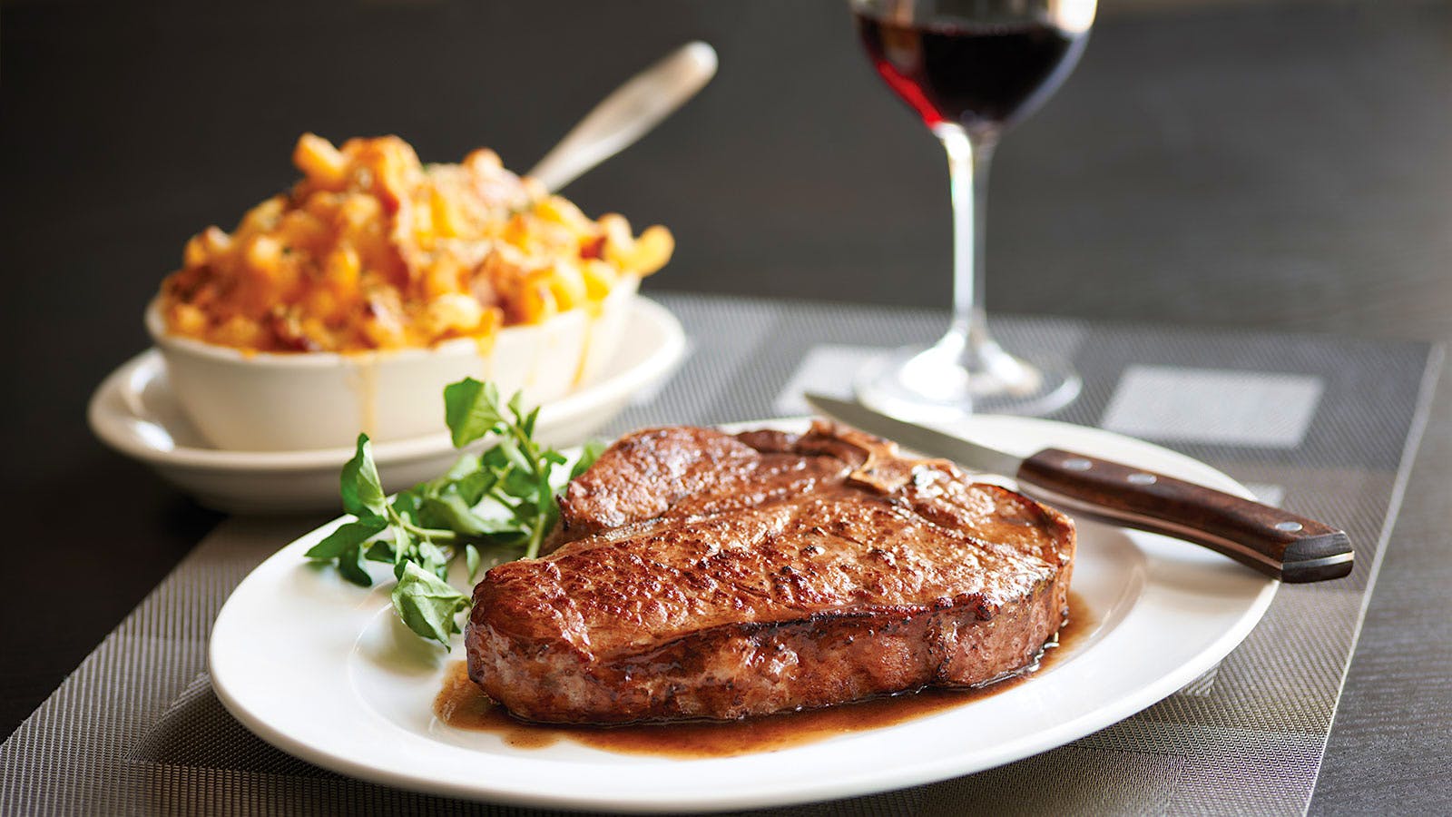 A porterhouse with a side of mac and cheese and a glass of red wine at Morton’s, the Steakhouse