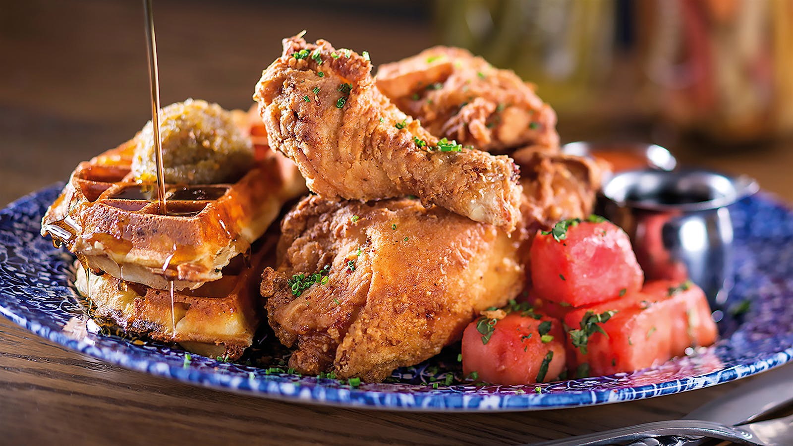 Syrup being poured over Yardbird’s fried chicken and waffles
