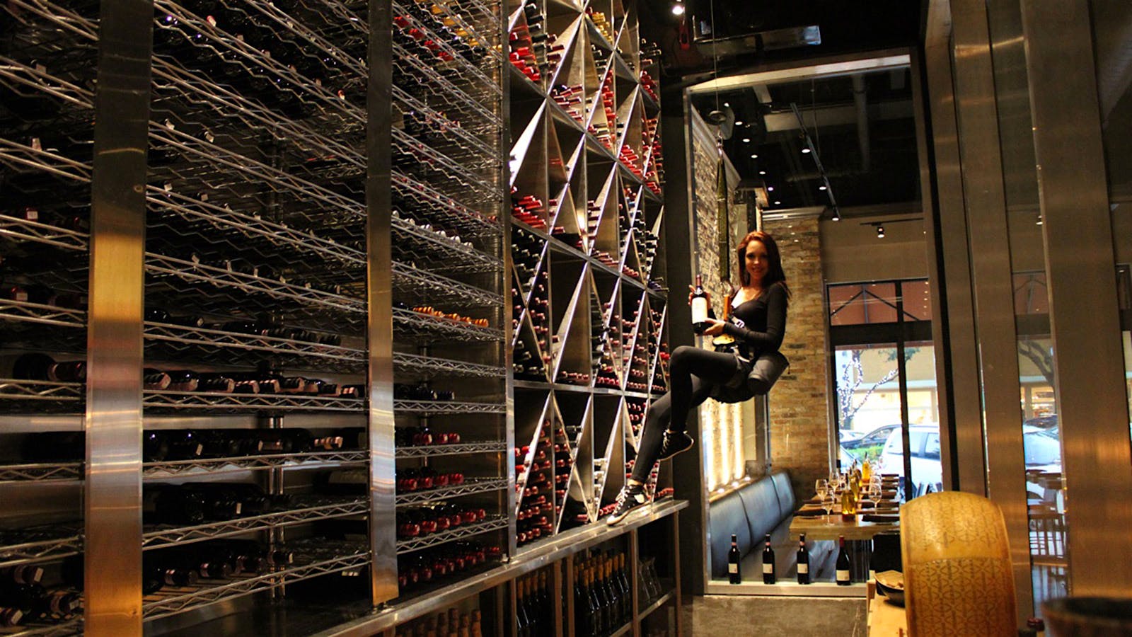 An employee in a harness floats down with a bottle from the wine display at Cibo Wine Bar