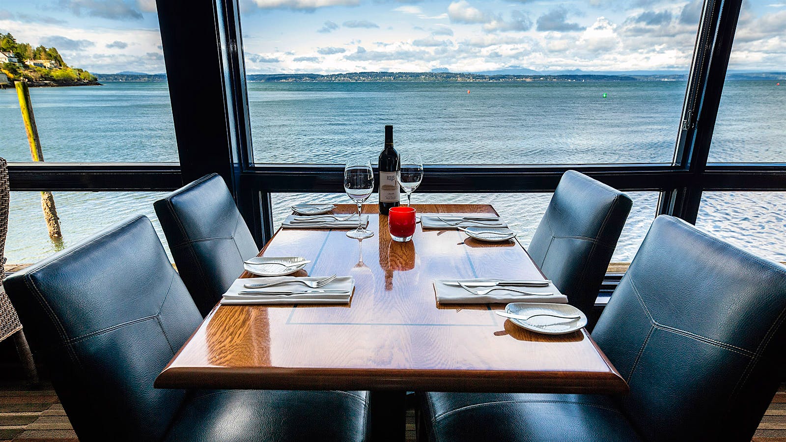 A table for four with a waterfront view and a bottle of wine at Ray’s Boathouse