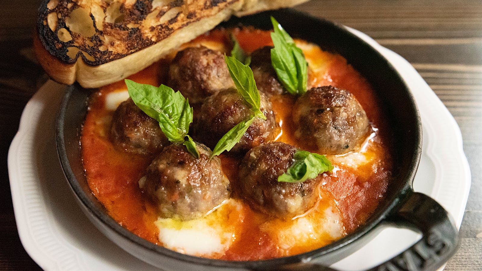 Cheesy meatballs with fresh basil and a slice of toasted bread at Monarch