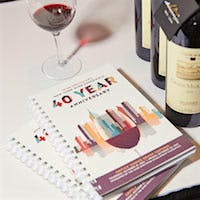 The 40th Anniversary Wine Experience Grand Tasting book next to bottles of red wine