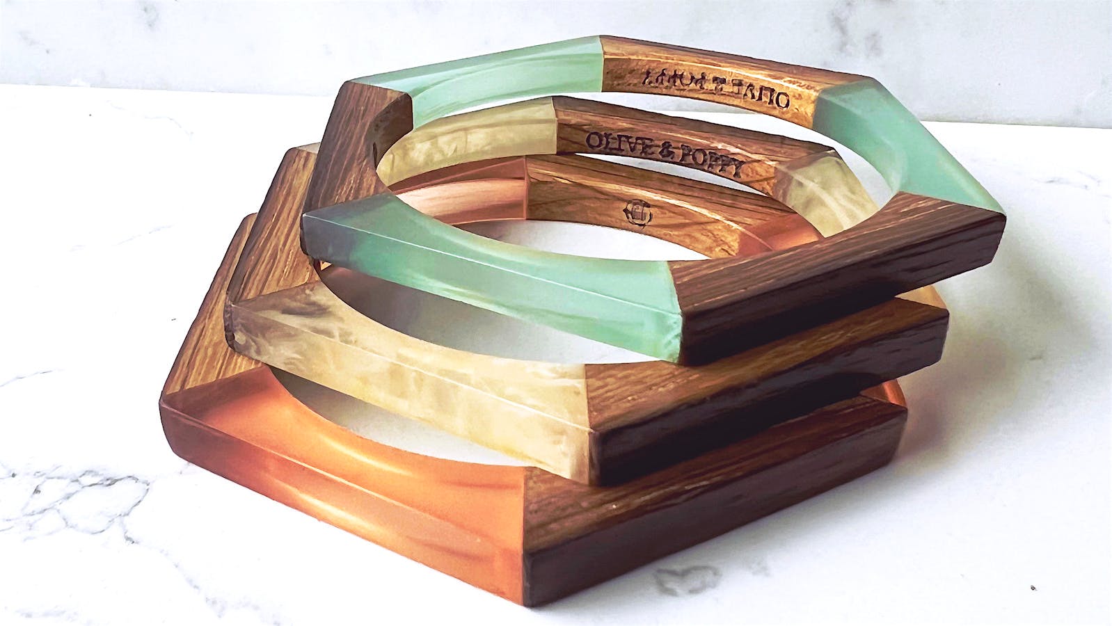  Three hexagonal Olive and Poppy bracelets made out of reclaimed wine-barrel wood and lucite] 