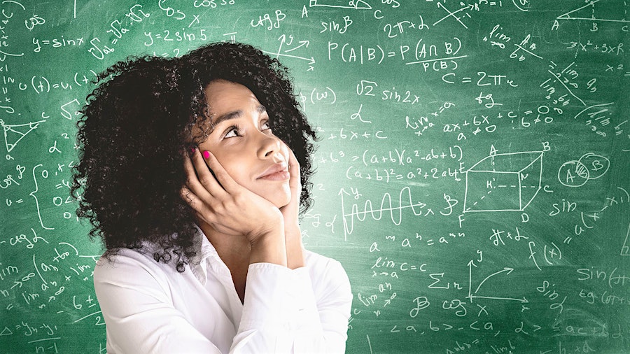 A person in front of a chalkboard covered in mathematical formulas
