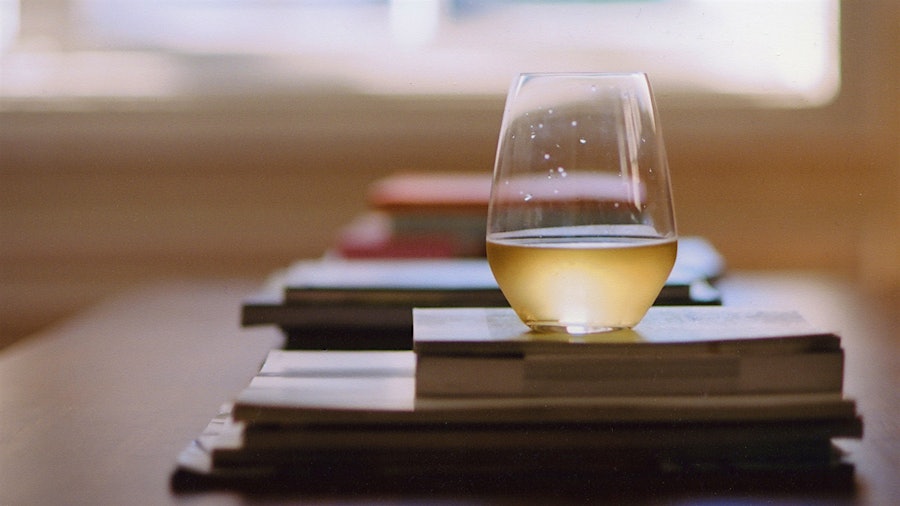 A glass of white wine on a stack of books
