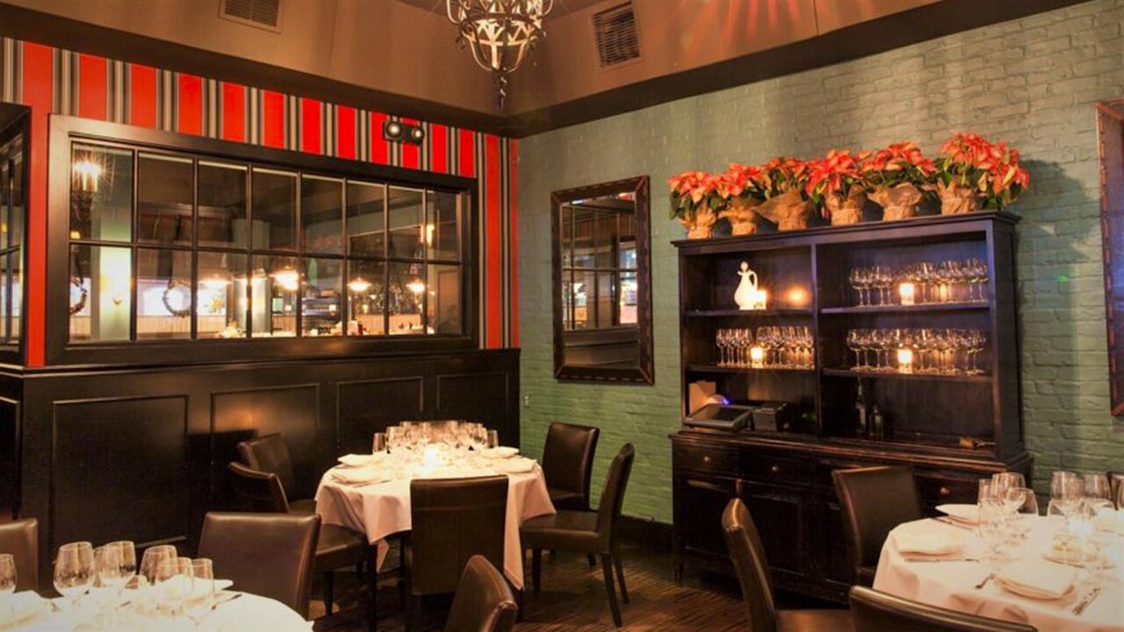  Dining room of Osteria Mozza with tables set for service and a cabinet holding rows of wine glasses