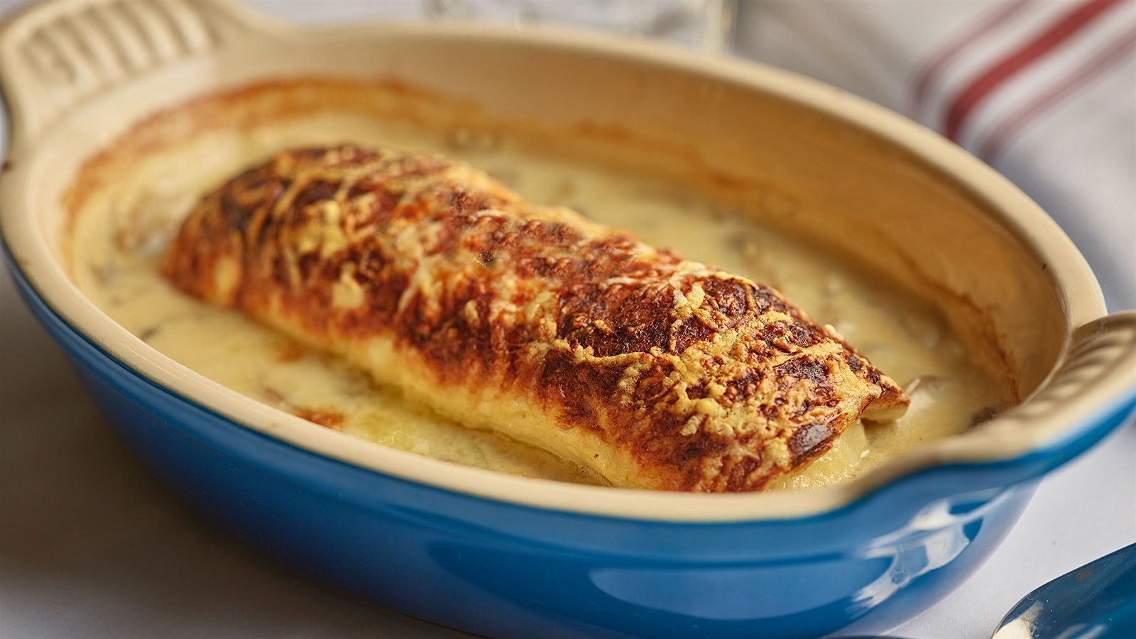     A blue and cream ceramic bowl containing a quenelle of pike au gratin