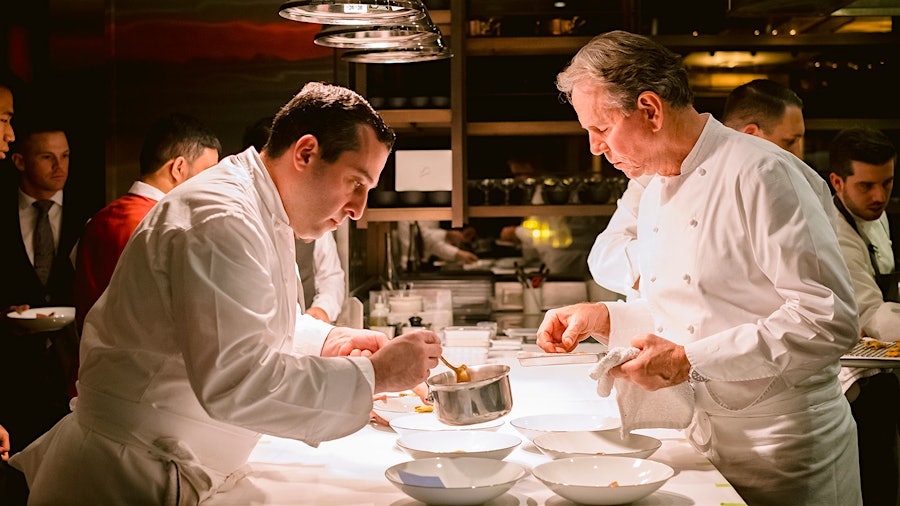Thomas Keller overseeing the preparation of food, with another chef