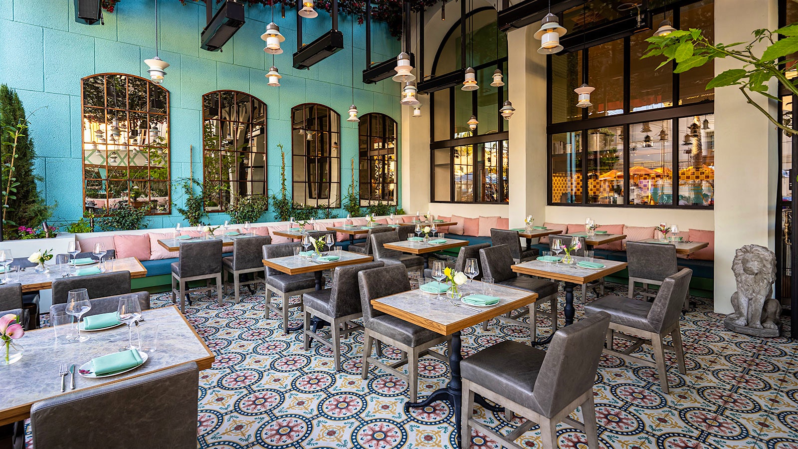  A dining room at Marisi with one aqua wall, pink-cushioned banquettes and a mosaic tiled floor