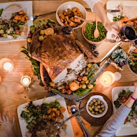 A cooked turkey, peas, sweet potatoes and other Thanksgiving dishes on a table, with people clinking glasses of red wineHoliday Edition: 99-Point Napa Cabernet, Classic Sonoma Chardonnay