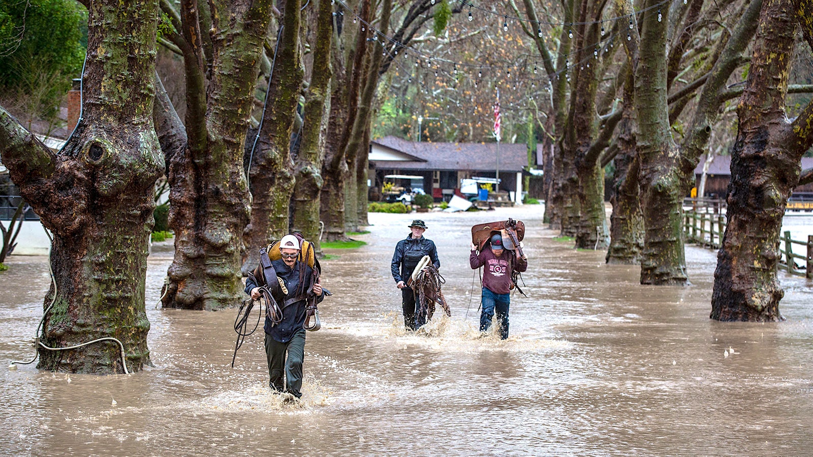  Solvang winery workers carry ranch gear through knee-high flood waters in California