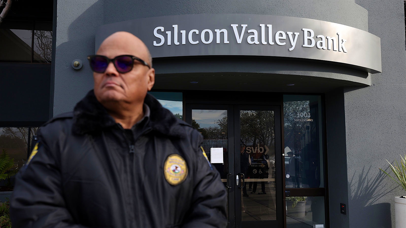  A guard stands watch outside Silicon Valley Bank's Santa Clara branch as customers are allowed to access their money.