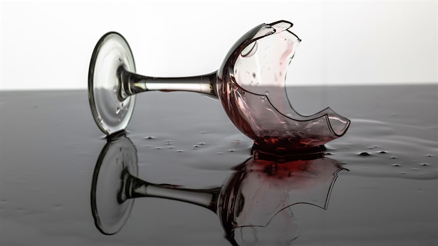 A broken wine glass with residue of red wine