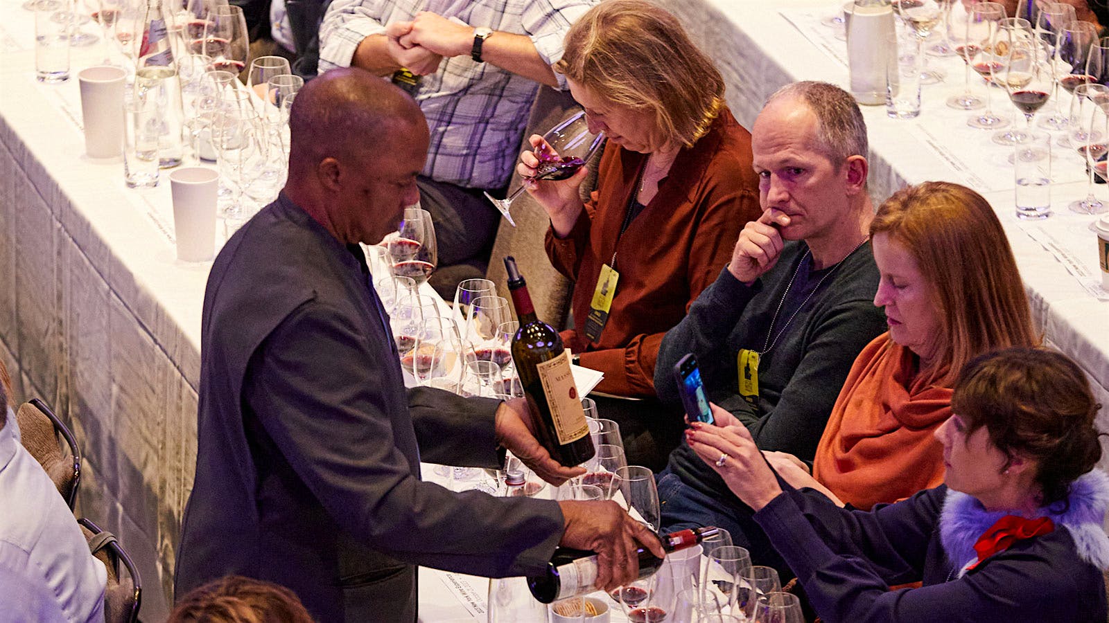  A server pouring Masseto wine while an audience member takes a picture of the bottle&nbsp;during the New York Wine Experience