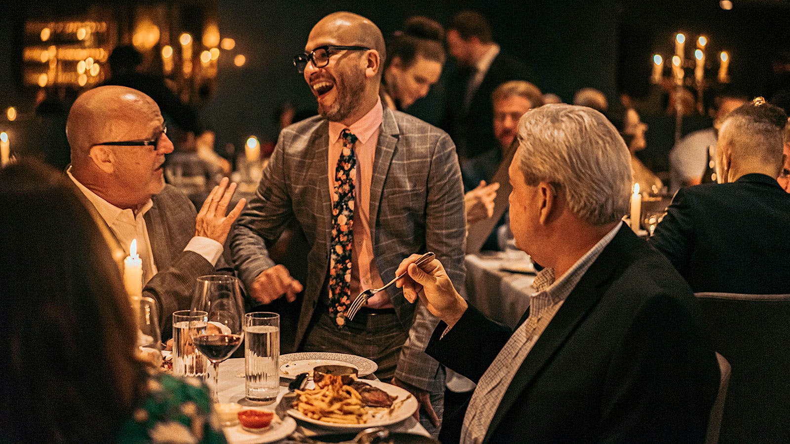  A staff member at Maple &amp; Ash laughs as a table of two guests eat steak and French fries
