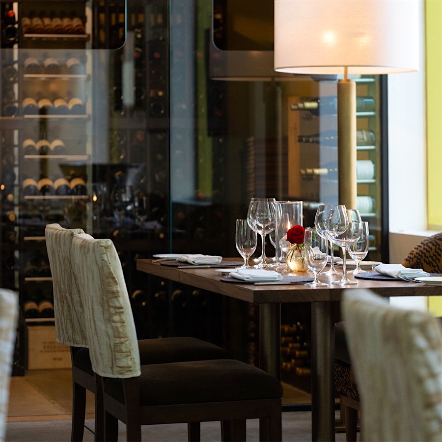  A table at Dry Creek Kitchen in front of a glass window, with a view into the new wine cellar and bottles therein