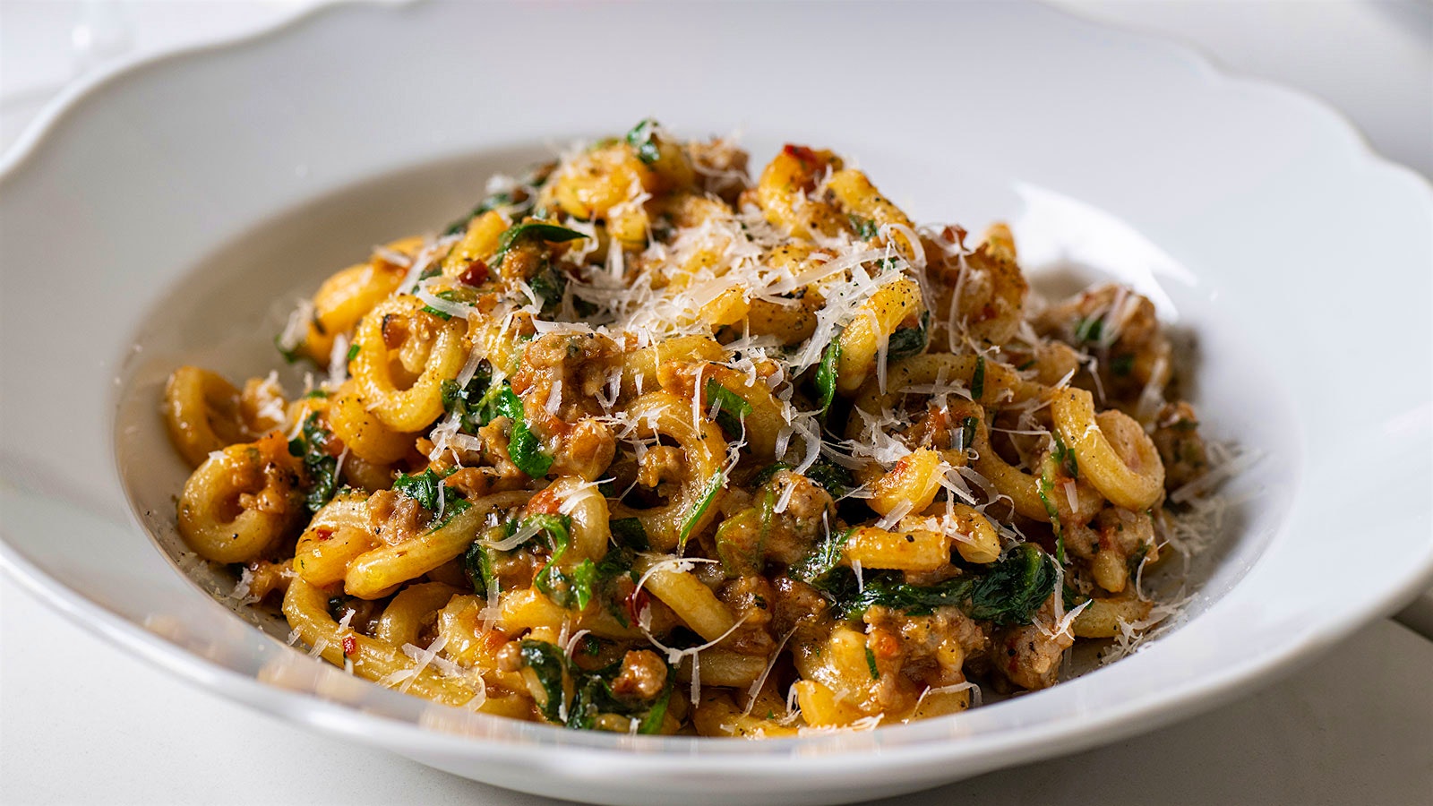  A plate of gramigna pasta with spicy sausage, spinach and Grana Padano cheese