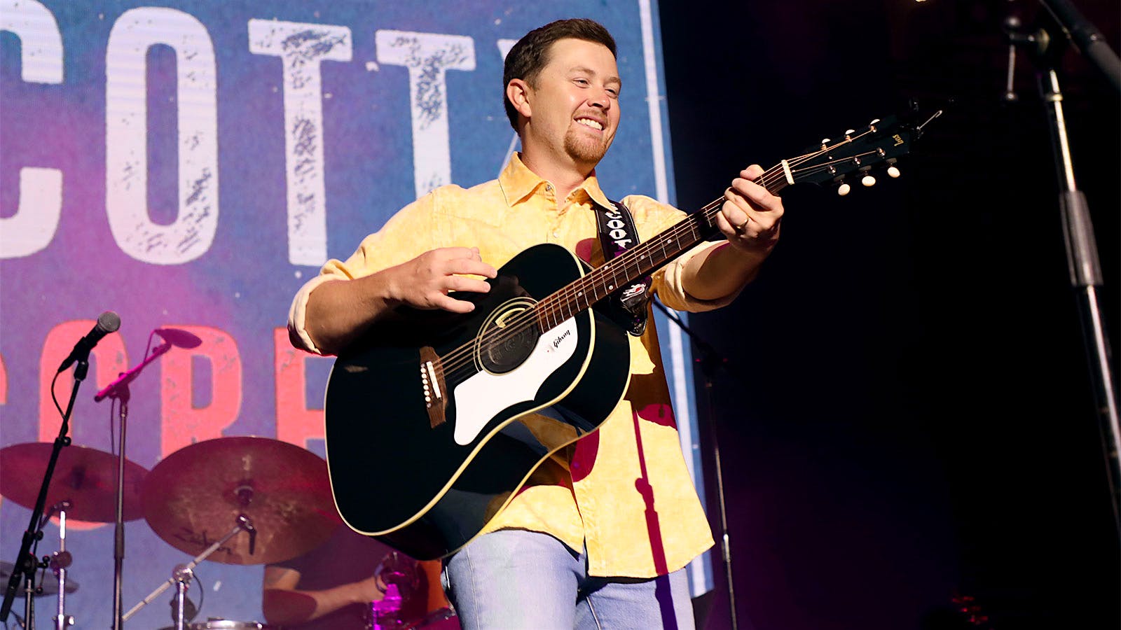 Scotty McCreery playing his guitar on stage during a concert in Nashville.