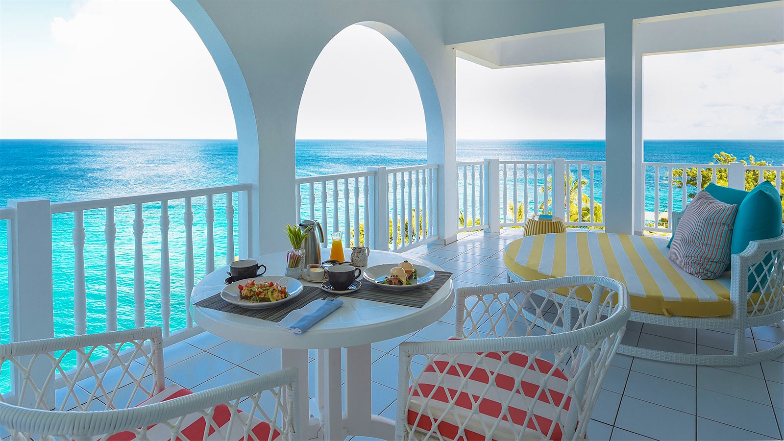  A set table on a balcony with white walls at Malliouhana Resort, overlooking the Caribbean Sea