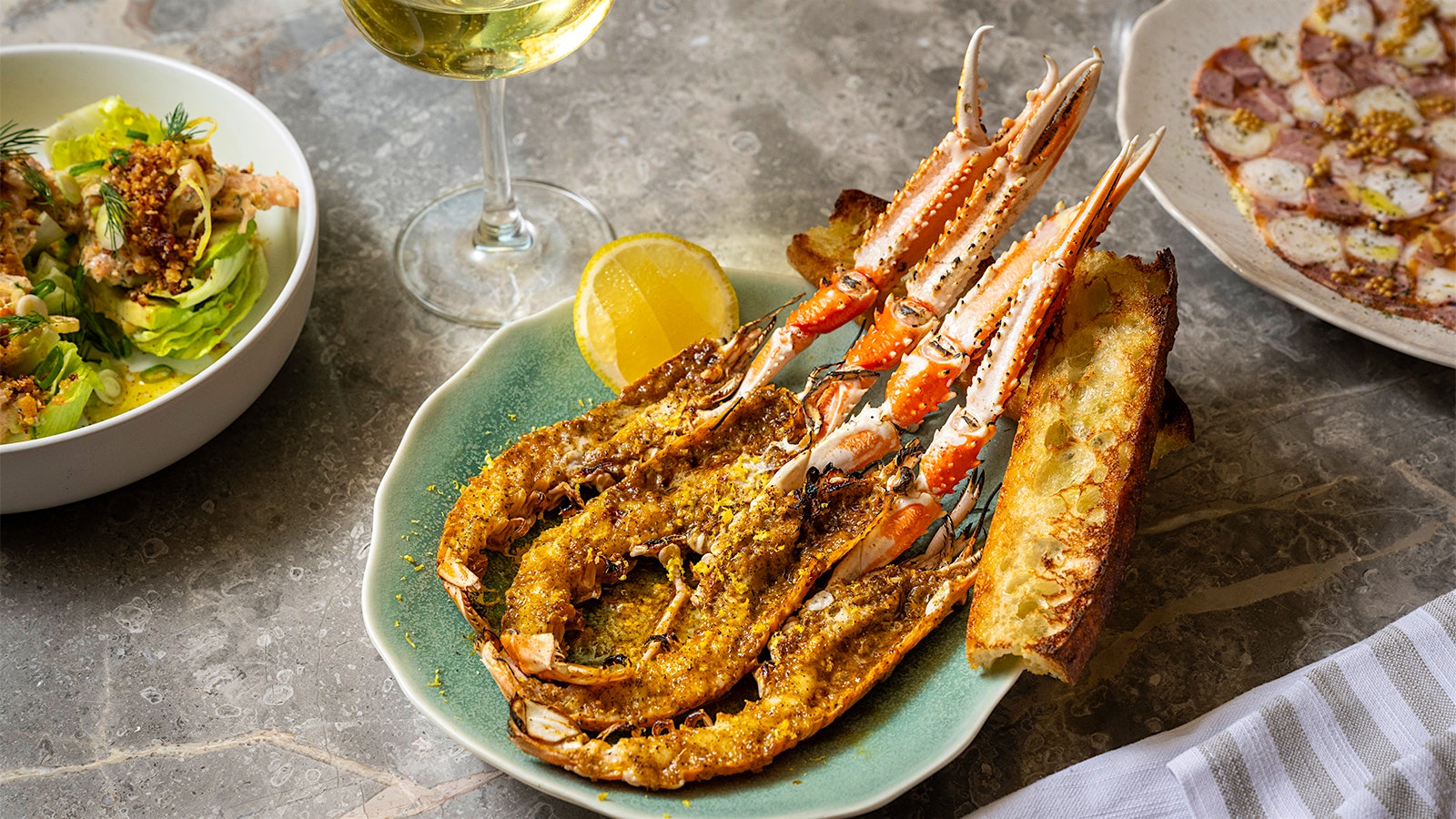  Plate of wild langoustines with New Orleans scampi butter at San Sabino, next to a glass of white wine