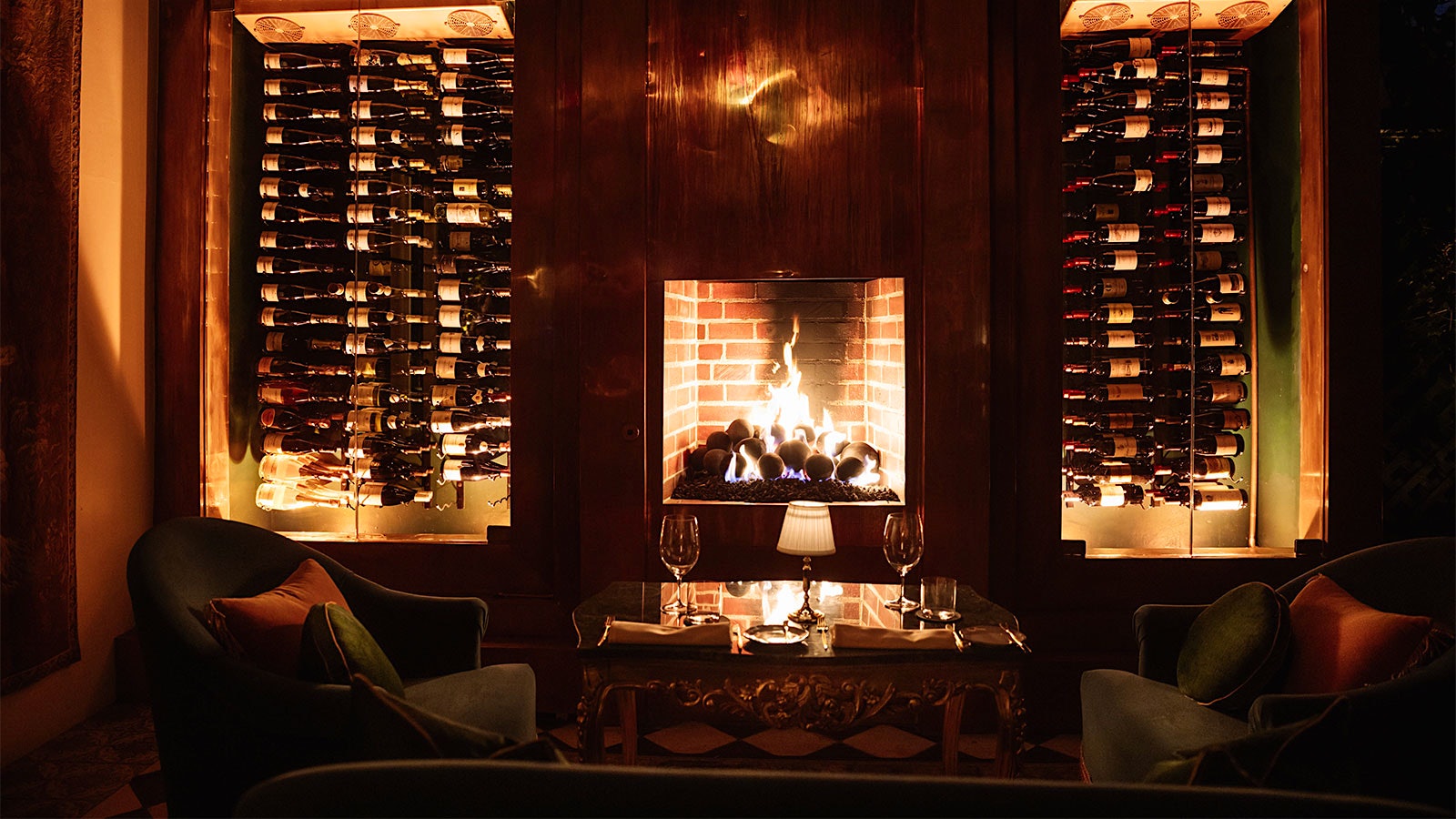  Two leather chairs next to a fireplace, surrounded by wine bottles.