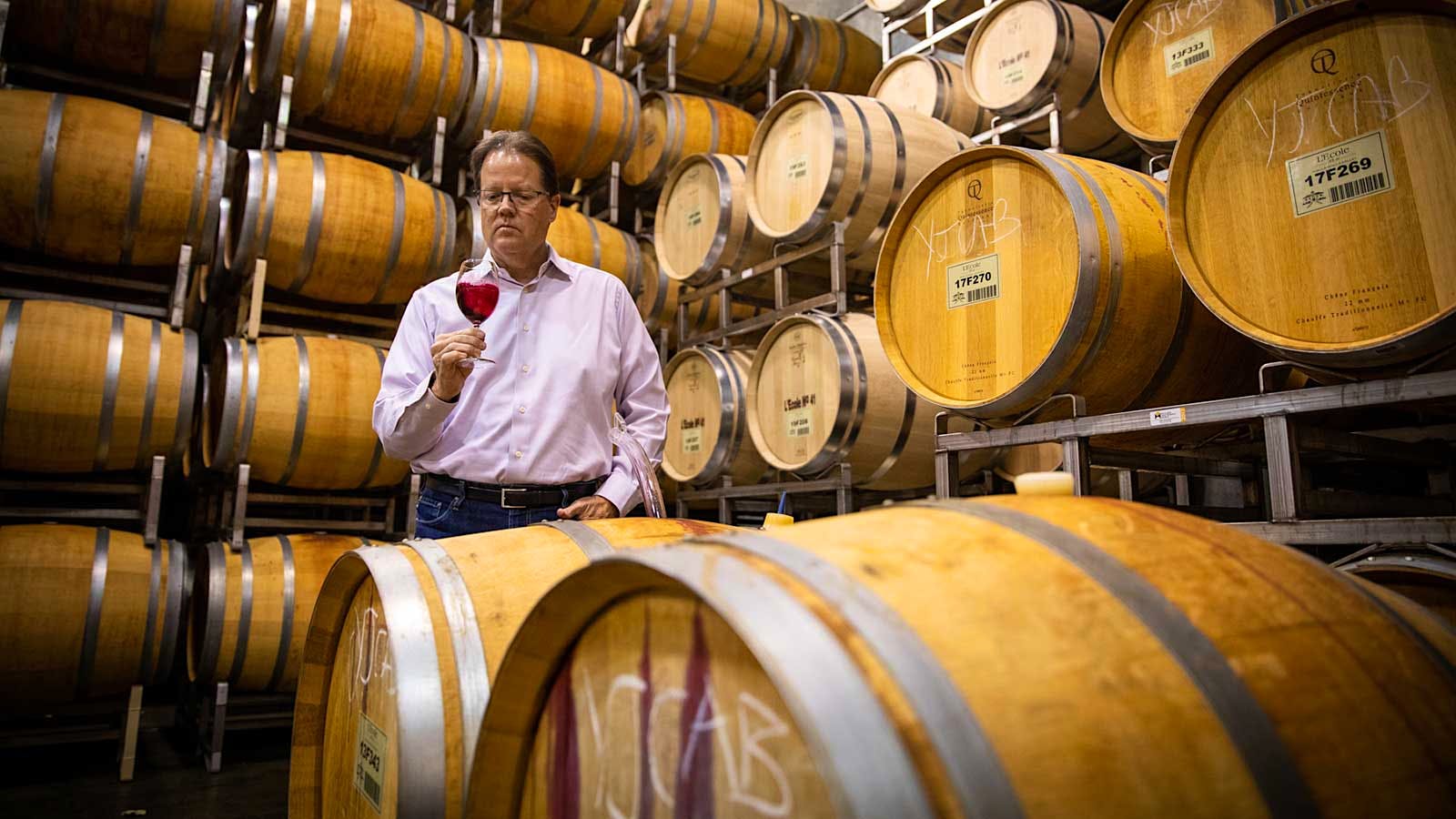 L'Ecole 41 winemaker Marty Clubb with a glass of wine in a barrel room