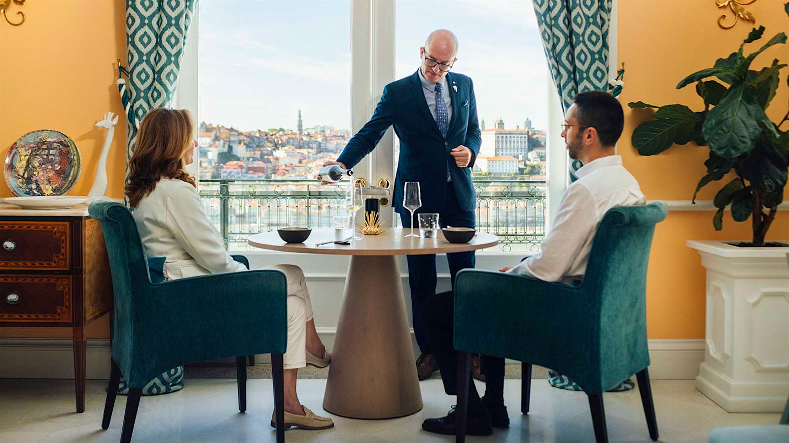  The Yeatman sommelier Paulo Padrão pouring wine for guests at a window-side table with a view of Vila Nova de Gaia and the Douro River