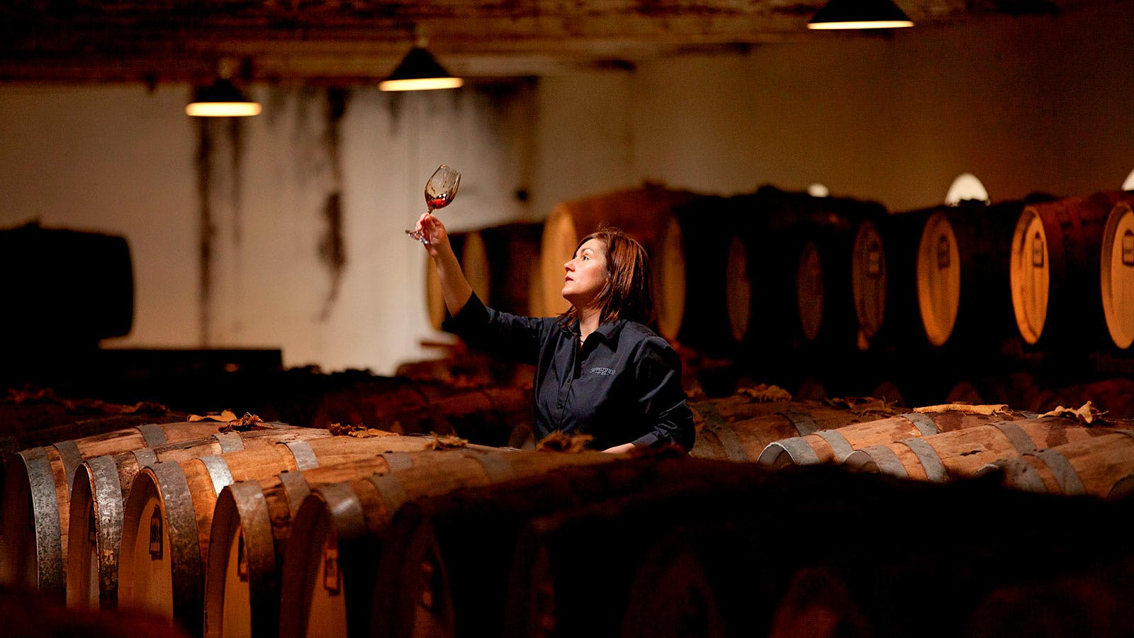 Seppeltsfield chief winemaker Fiona Donald holding a glass of red wine in a barrel room