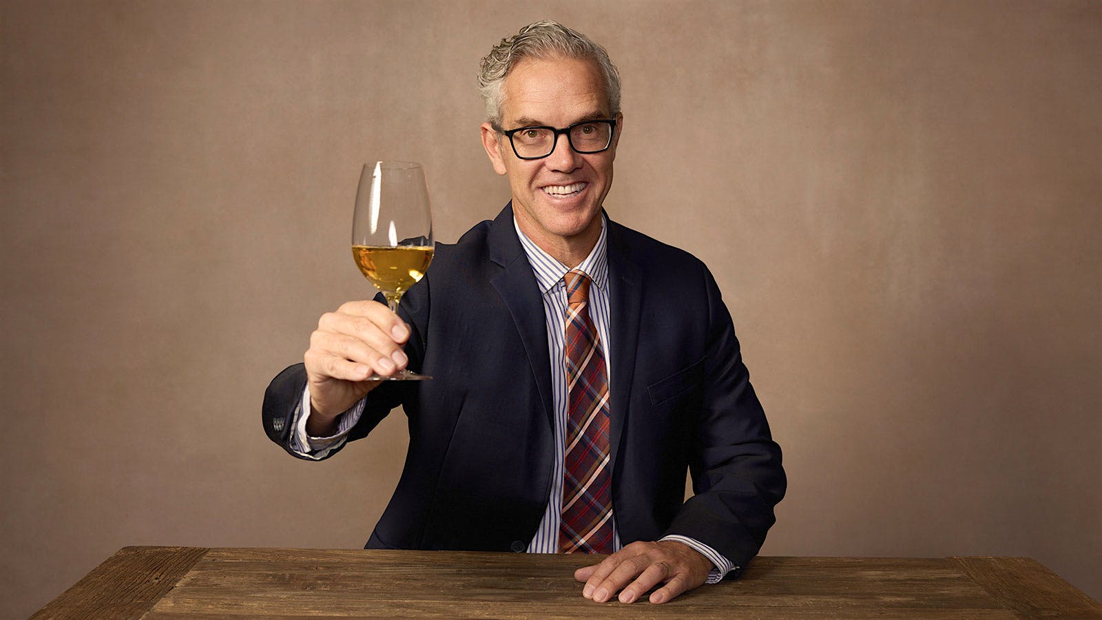 Hugh Davies holding a glass of sparkling wine.