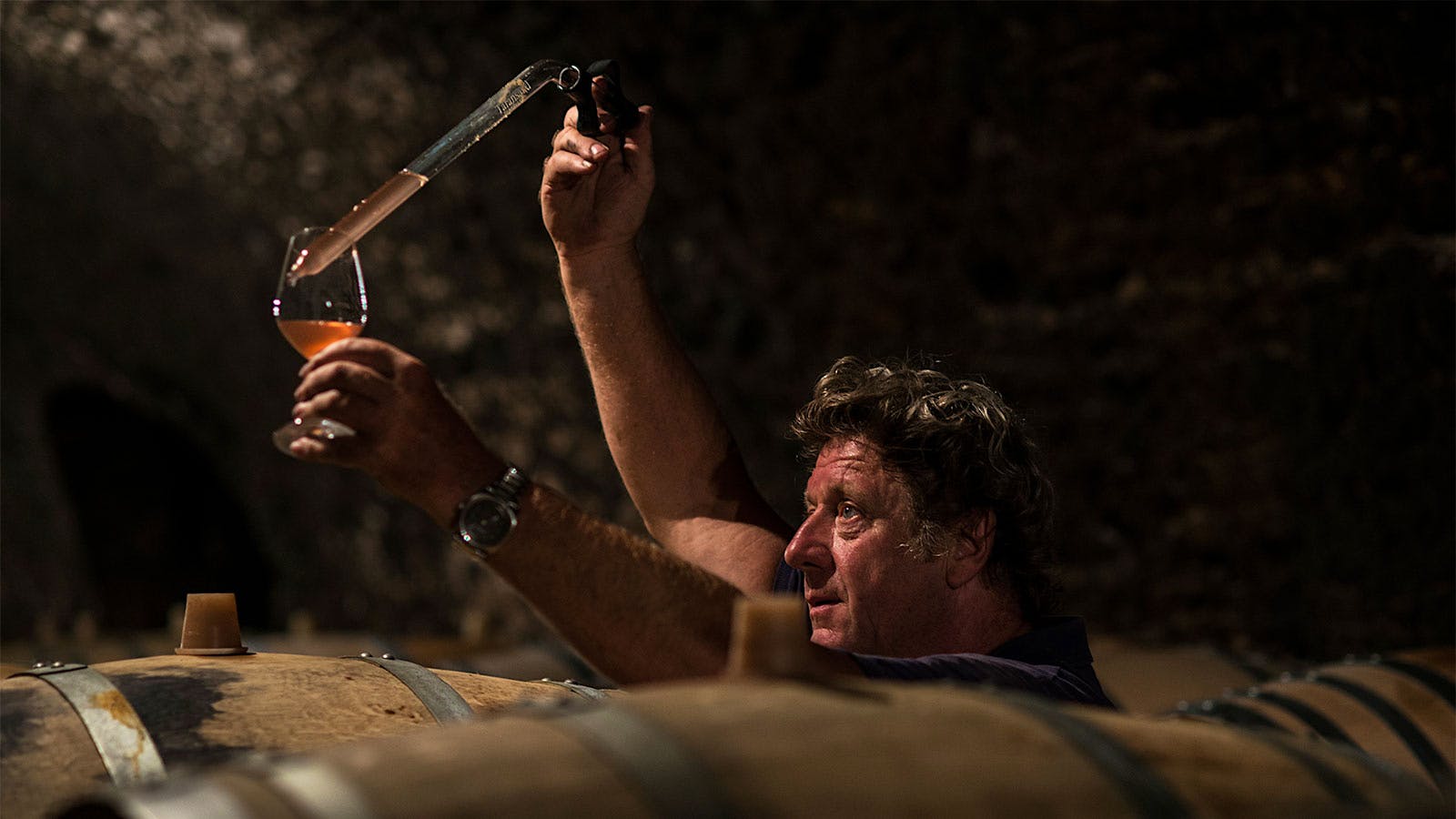 Champagne maker Anselme Selosse uses a pipette to take a sample from one of his barrels of base wine