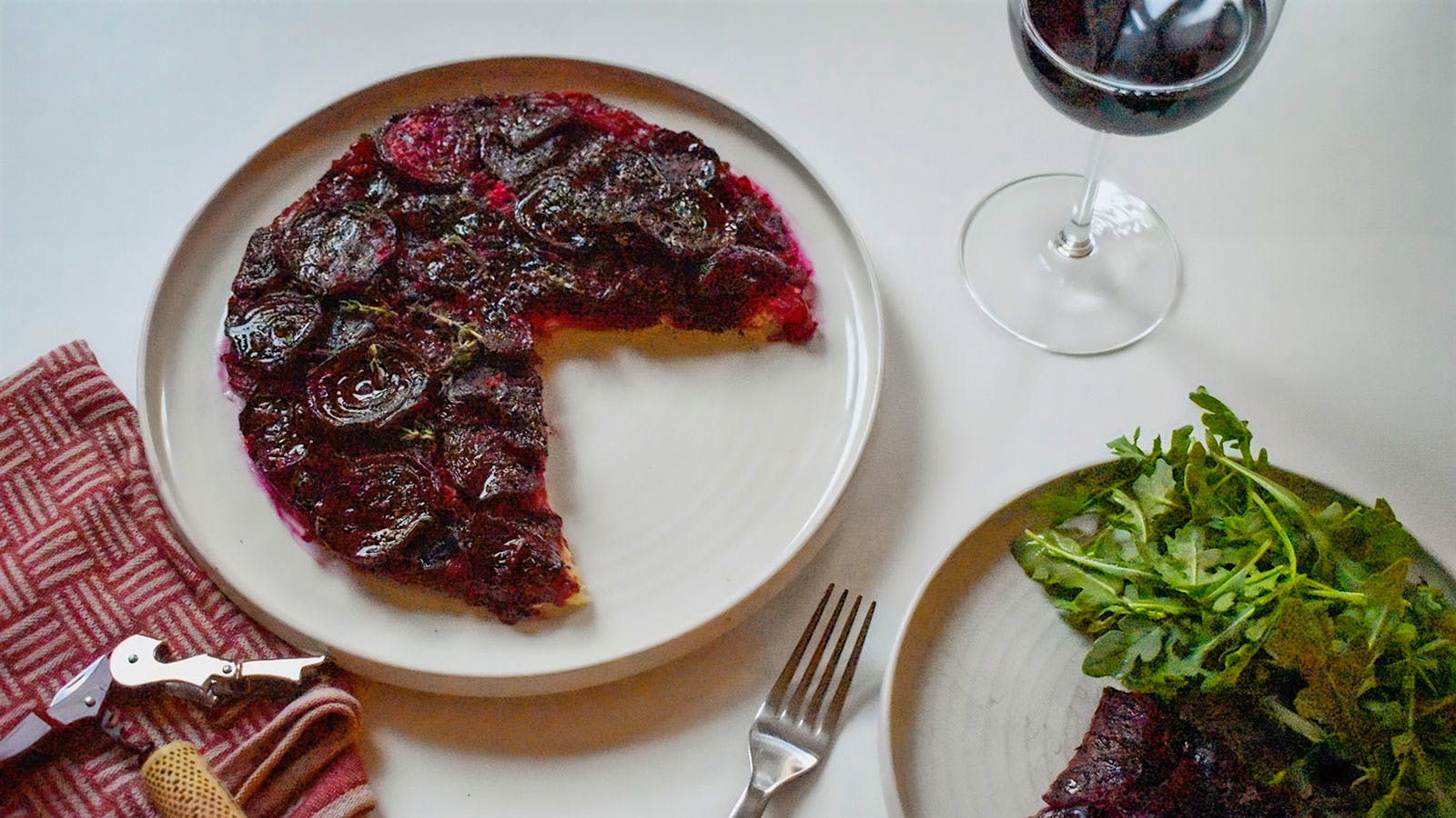 A beet tart served with a side salad and glass of red wine