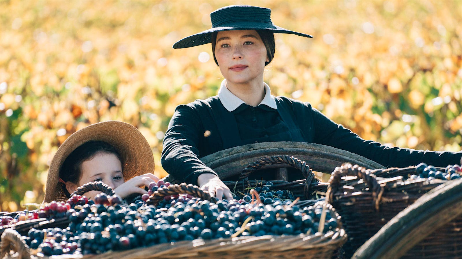  Haley Bennett as Madame Barbe-Nicole Clicquot Ponsardin in &ldquo;Widow Clicquot,&rdquo; next to a cart filled with grapes