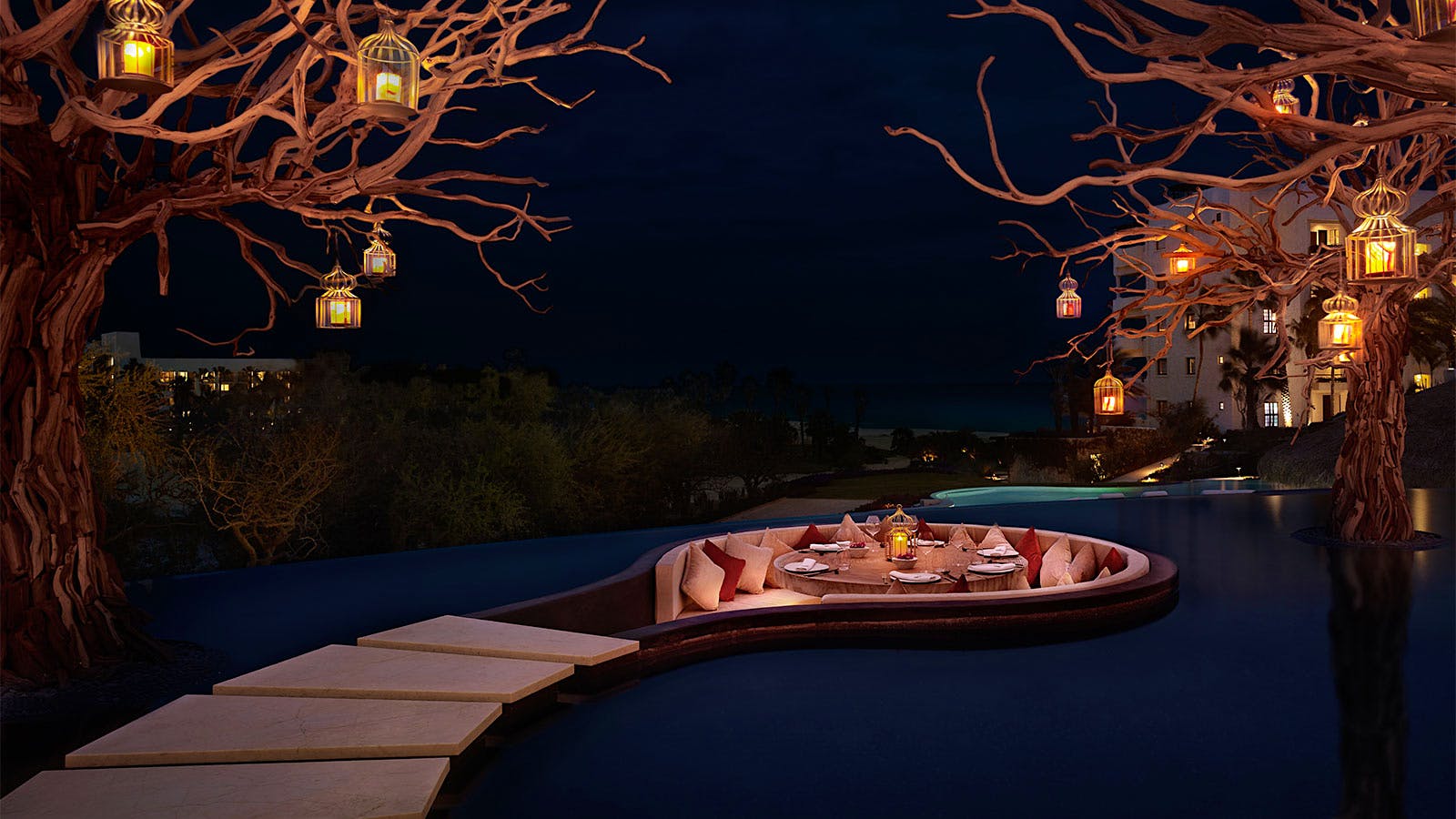A private dining space in the middle of an infinity pool, surrounded by ornamental trees, at Arbol in San Jose del Cabo