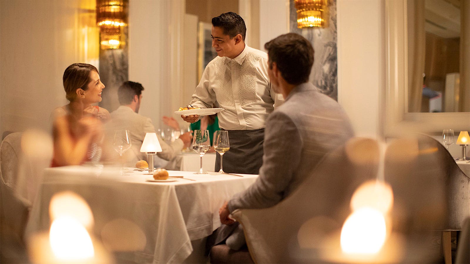  A server placing plates in front of guests at Lumi&egrave;re in Canc&uacute;n.