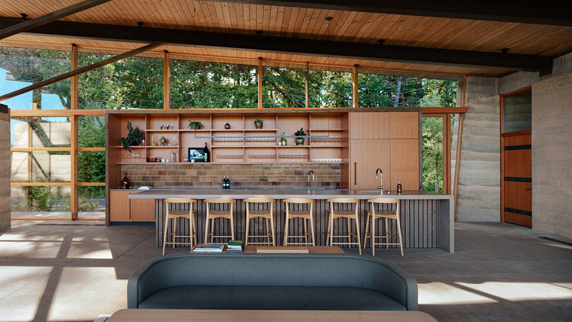  The interior of Rodeo HIlls tasting room with large windows providing a view of the vineyard and forest outside