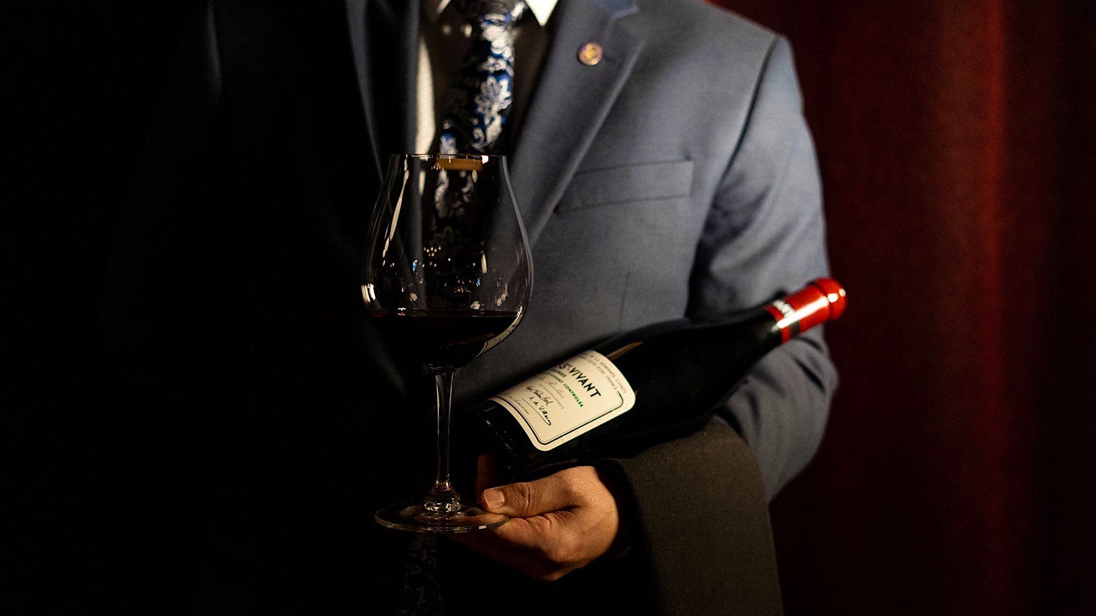  A waiter holding a bottle and glass of Burgundy at Marcel