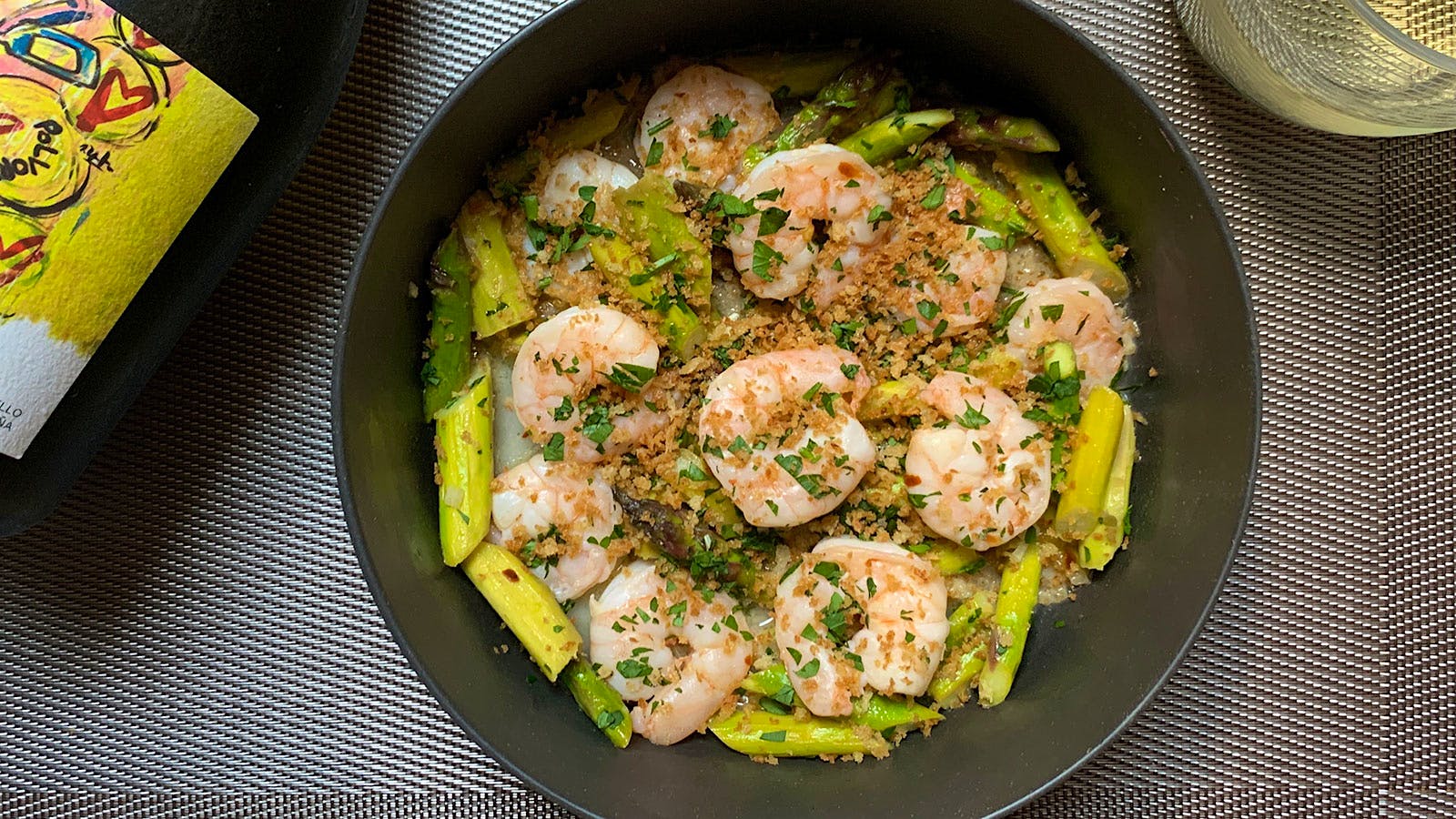 A bowl of shrimp and asparagus with breadcrumbs on top