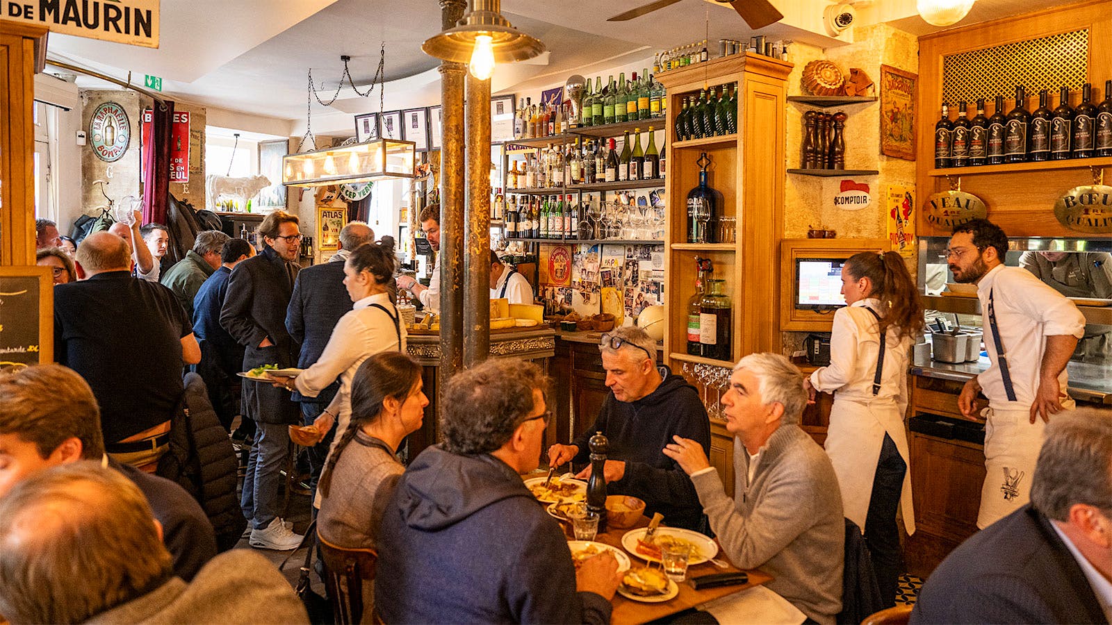  Le Bon Georges&rsquo;s bustling dining room and bar, with bottles of wine and spirits on shelves along the walls