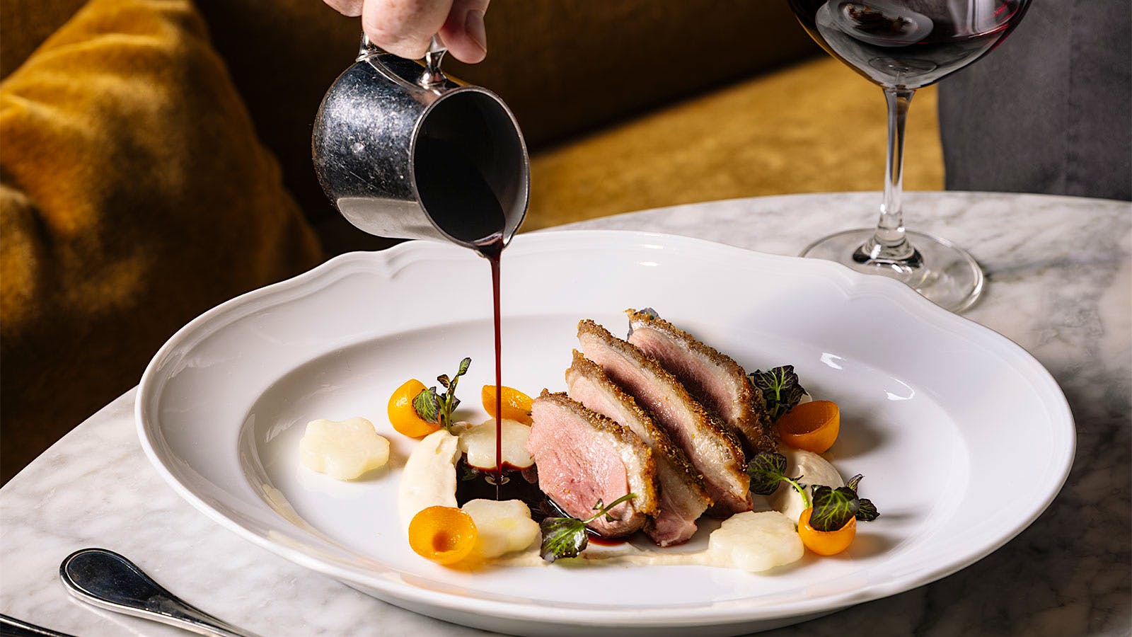  Selby's honey-lacquered duck breast with bigarade sauce being poured over it
