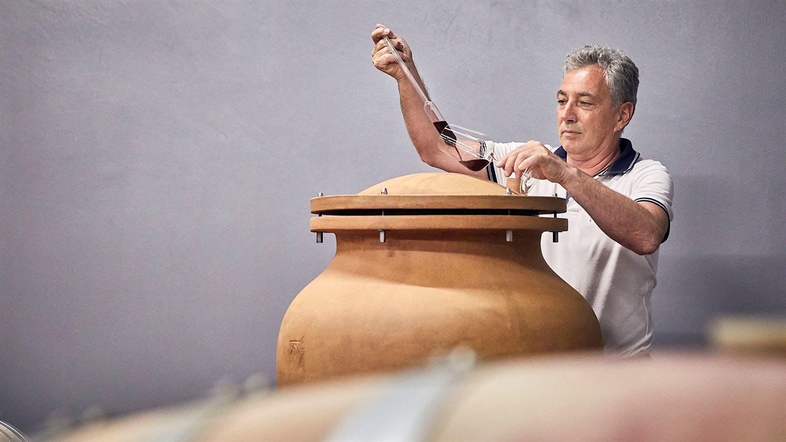  Longtime Abbazia di Novacella winemaker Celestino Lucin removing red wine from an concrete vat