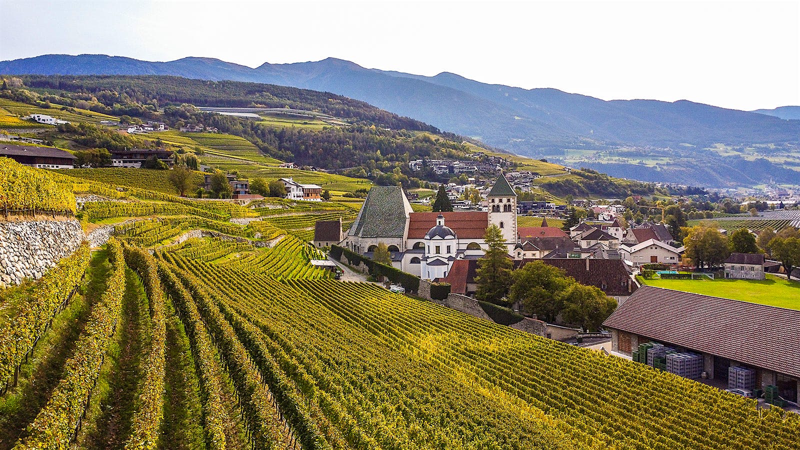  An autumn view of Abbazia di Novacella, its vineyard slopes and the mountains behind