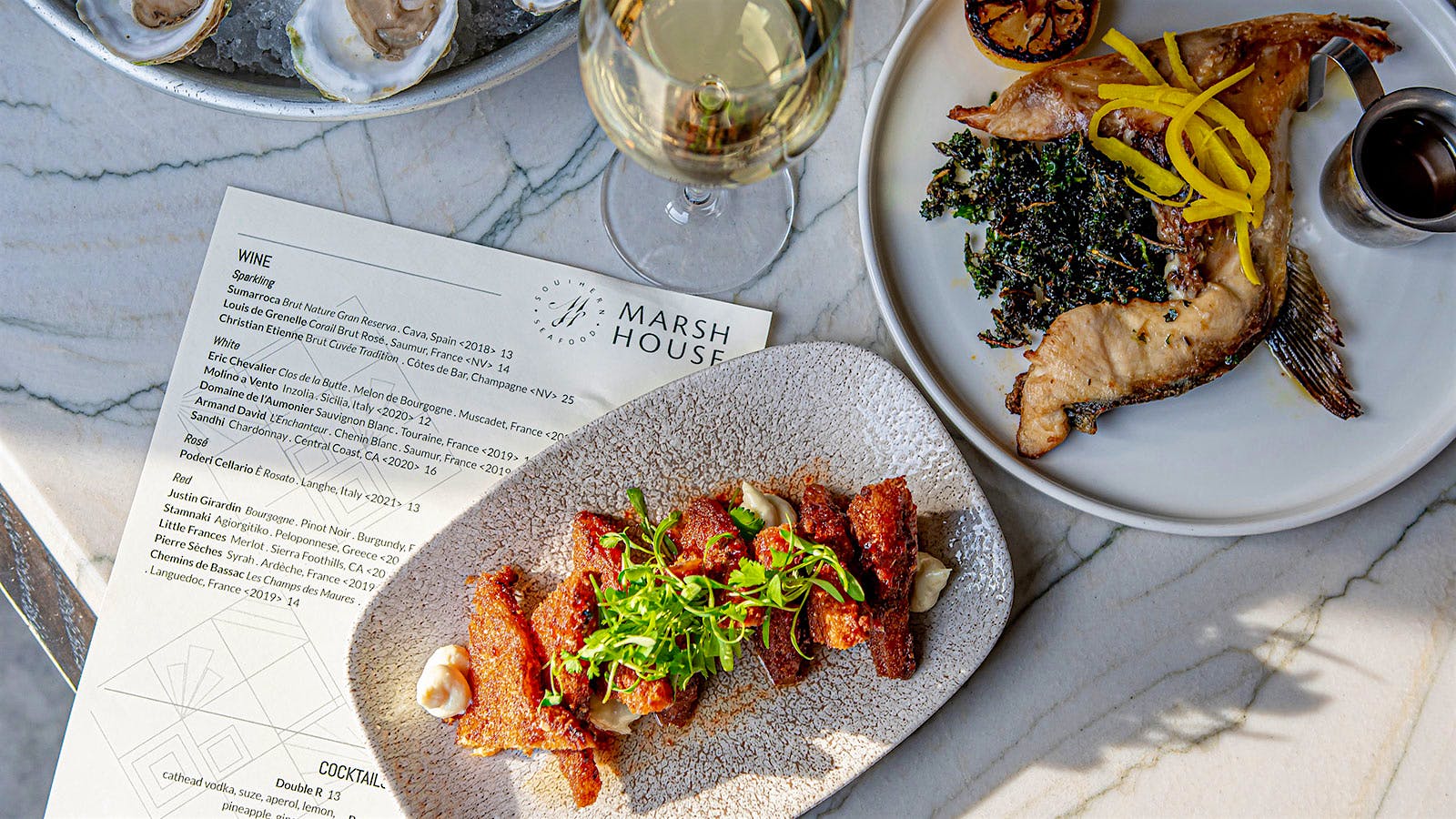  Seafood dishes, glasses of white wine and a menu from Marsh House in Nashville, Tennessee